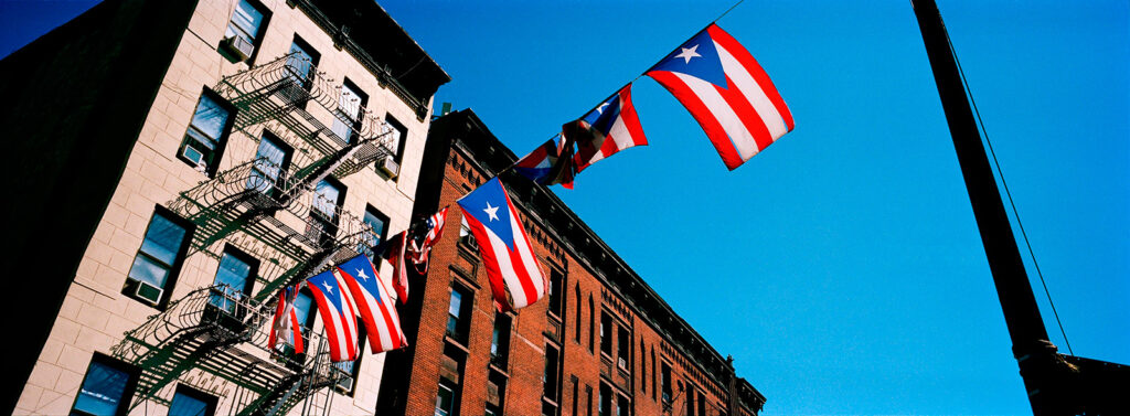 A row of flags of Puerto Rico hung from strings that run along a street.