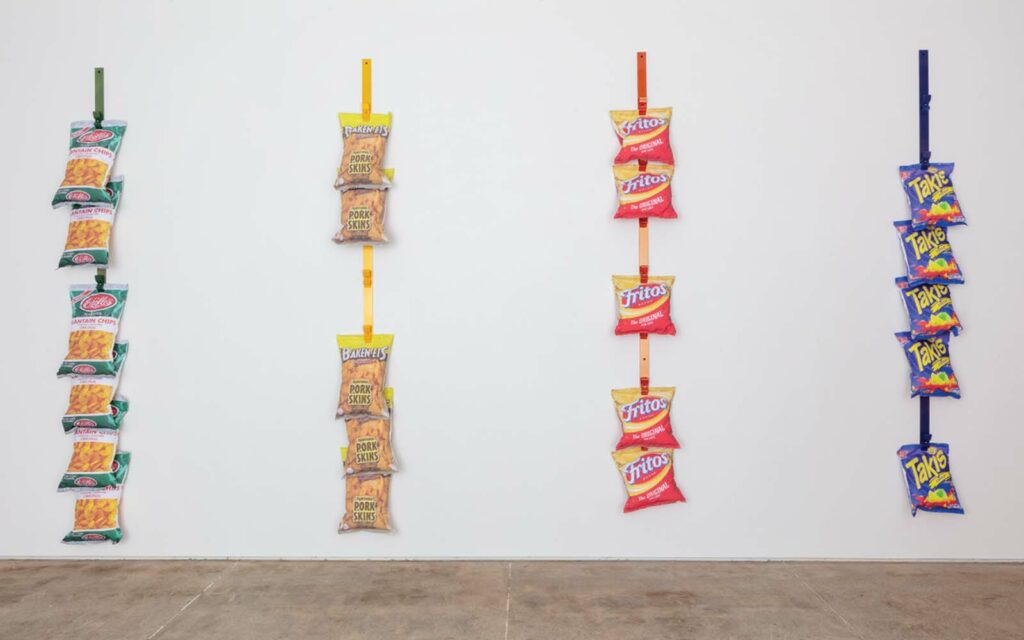 over life-size sculptural Racks mimic a typical display system for bags of chips–in this case, platanitos, chicharrones, corn chips, and takis